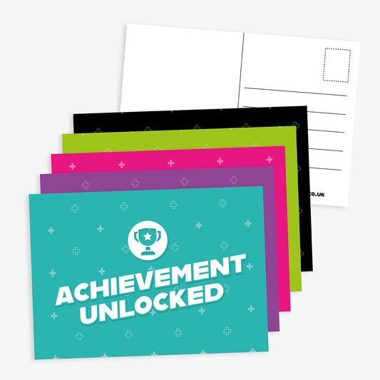 Set of brightly coloured A6 postcards with the message 'Achievement Unlocked' on the front, featuring a trophy icon; reverse side includes space for writing and address.