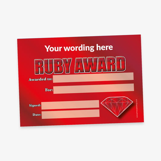 A shiny red 'Ruby Award' certificate with a red gradient background. Bold silver and red text reads 'RUBY AWARD' beneath the placeholder 'Your wording here'. The certificate includes labelled sections for 'Awarded to:', 'For:', 'Signed:', and 'Date:', each with a rectangular space for writing. A faceted ruby gemstone illustration appears in the bottom right corner.