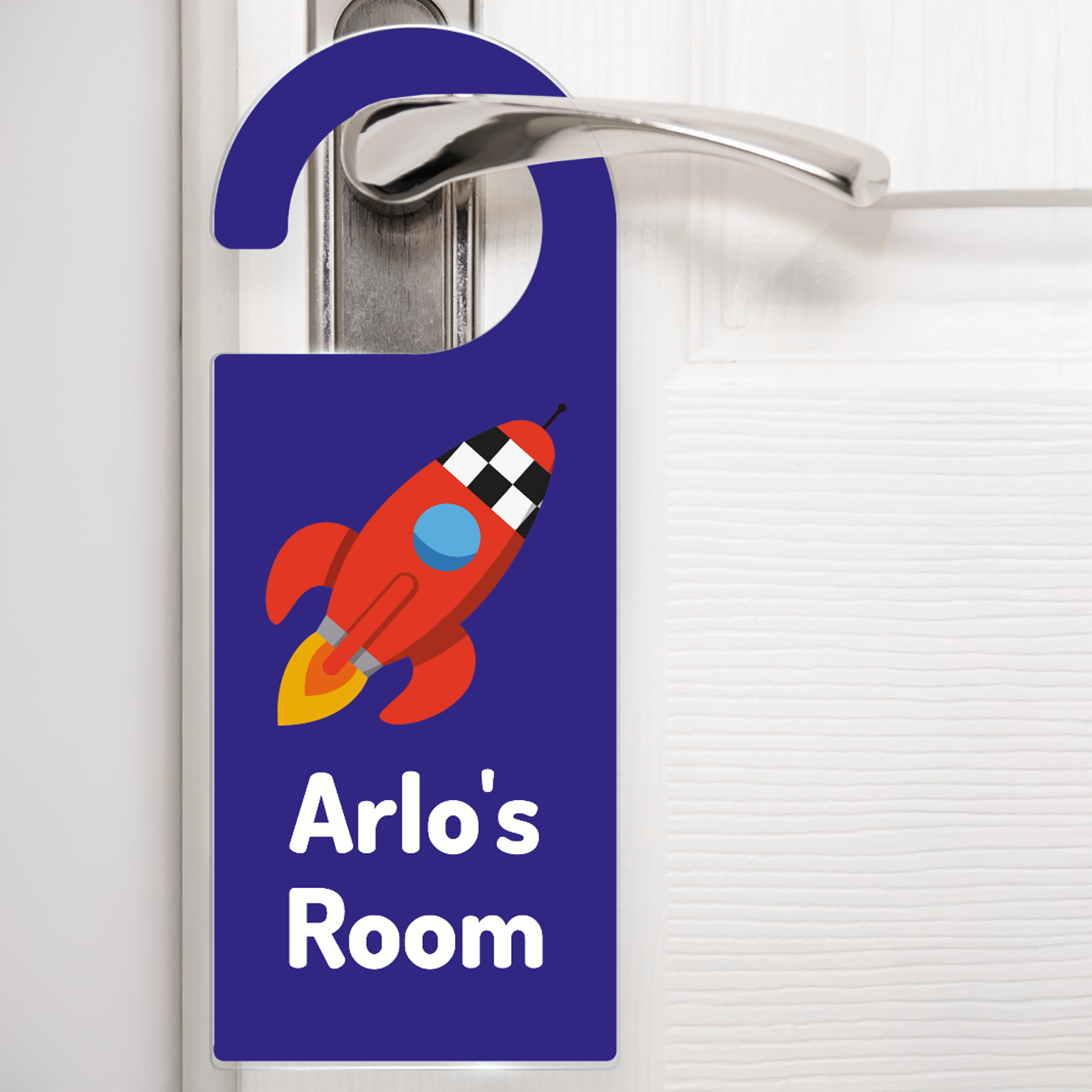 A dark blue door hanger hanging on a silver handle, featuring a cartoon red rocket emitting flames above the text 'Arlo's Room' in white letters. The design is playful and child-friendly, ideal for decorating a child's bedroom door.