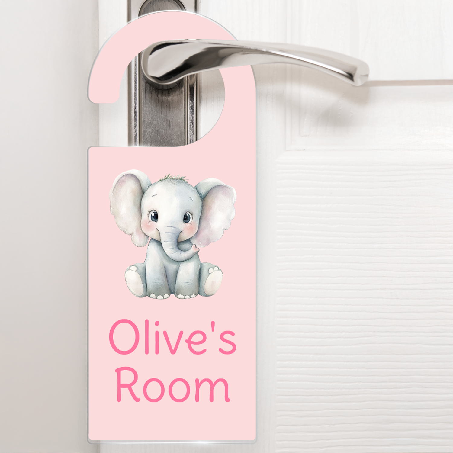 A pale pink door hanger hanging on a silver handle, featuring a cute cartoon elephant above the text 'Olive's Room' in darker pink letters. The design is playful and child-friendly, ideal for decorating a child's bedroom door.