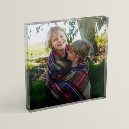 A square acrylic photo block featuring a photo of two children laughing.  The block has a glossy, freestanding design ideal for display.