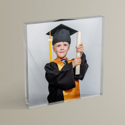 A square acrylic photo block featuring a photo of a child graduating nursery.  The block has a glossy, freestanding design ideal for display.