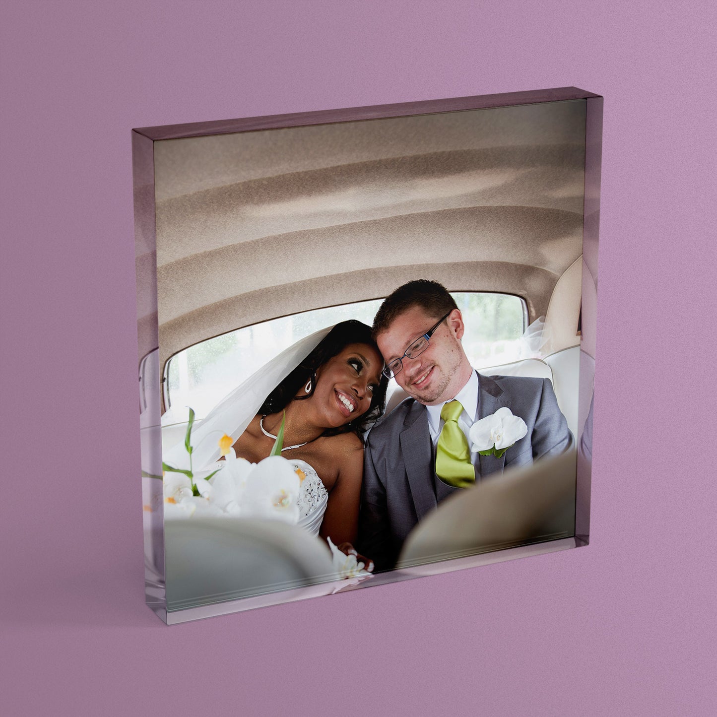 A square acrylic photo block featuring a photo of a couple on their wedding day in the back of a car.  The block has a glossy, freestanding design ideal for display.