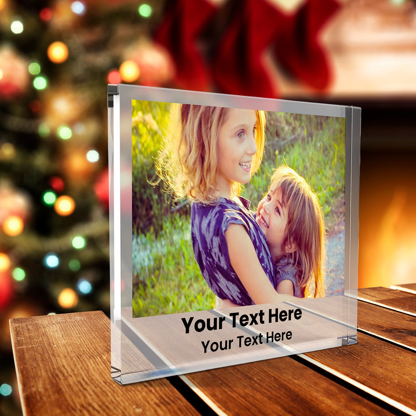A square acrylic photo block featuring a family photo. The image shows two smiling children. Beneath the photo, printed placeholder text reads 'Your Text Here' followed by  'Your Text Here'. The block has a glossy, freestanding design ideal for display.