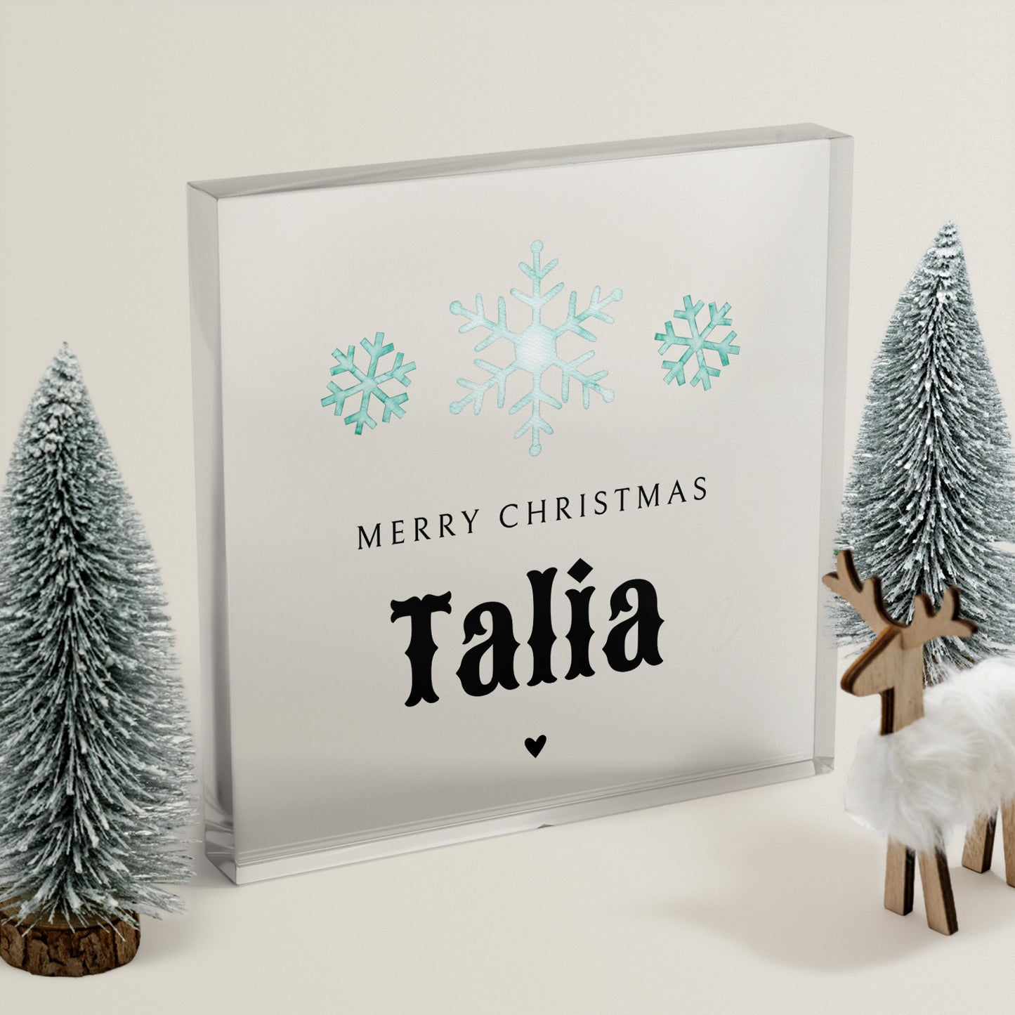 Framed Christmas card with snowflakes and 'Merry Christmas Talia' text, surrounded by decorative trees and a deer.