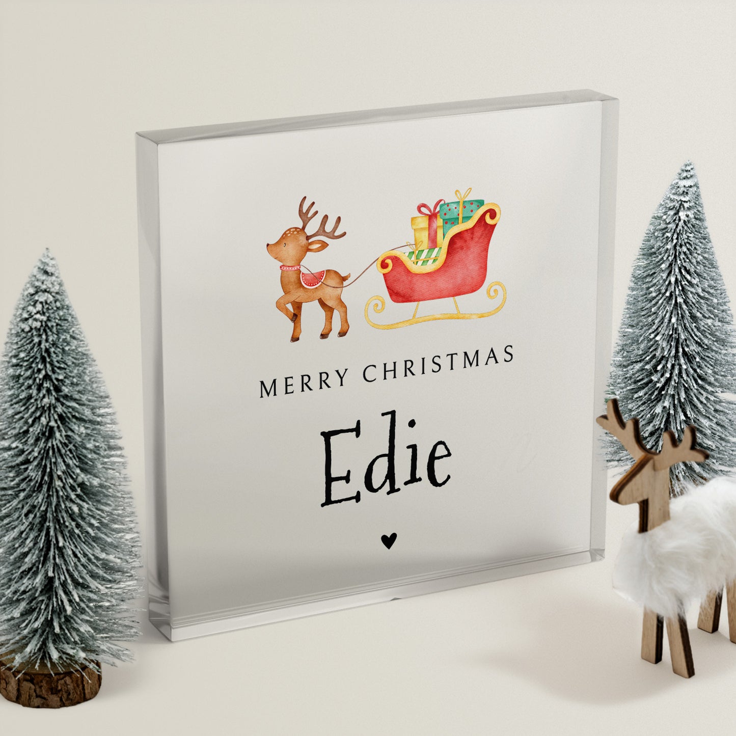 Framed Christmas-themed artwork with reindeer and sleigh, surrounded by decorative trees and deer figurines.