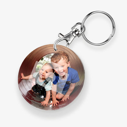 A personalised keyring featuring a circular photo frame design with a metal keychain and clasp. The photo shows a two children crawling through a tunnel. 