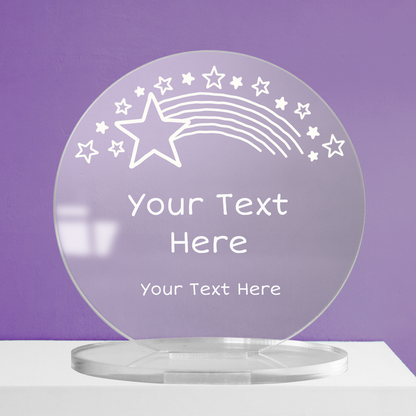 Clear round acrylic award with customisable text, featuring a shooting star and star motif design, displayed against a purple background.