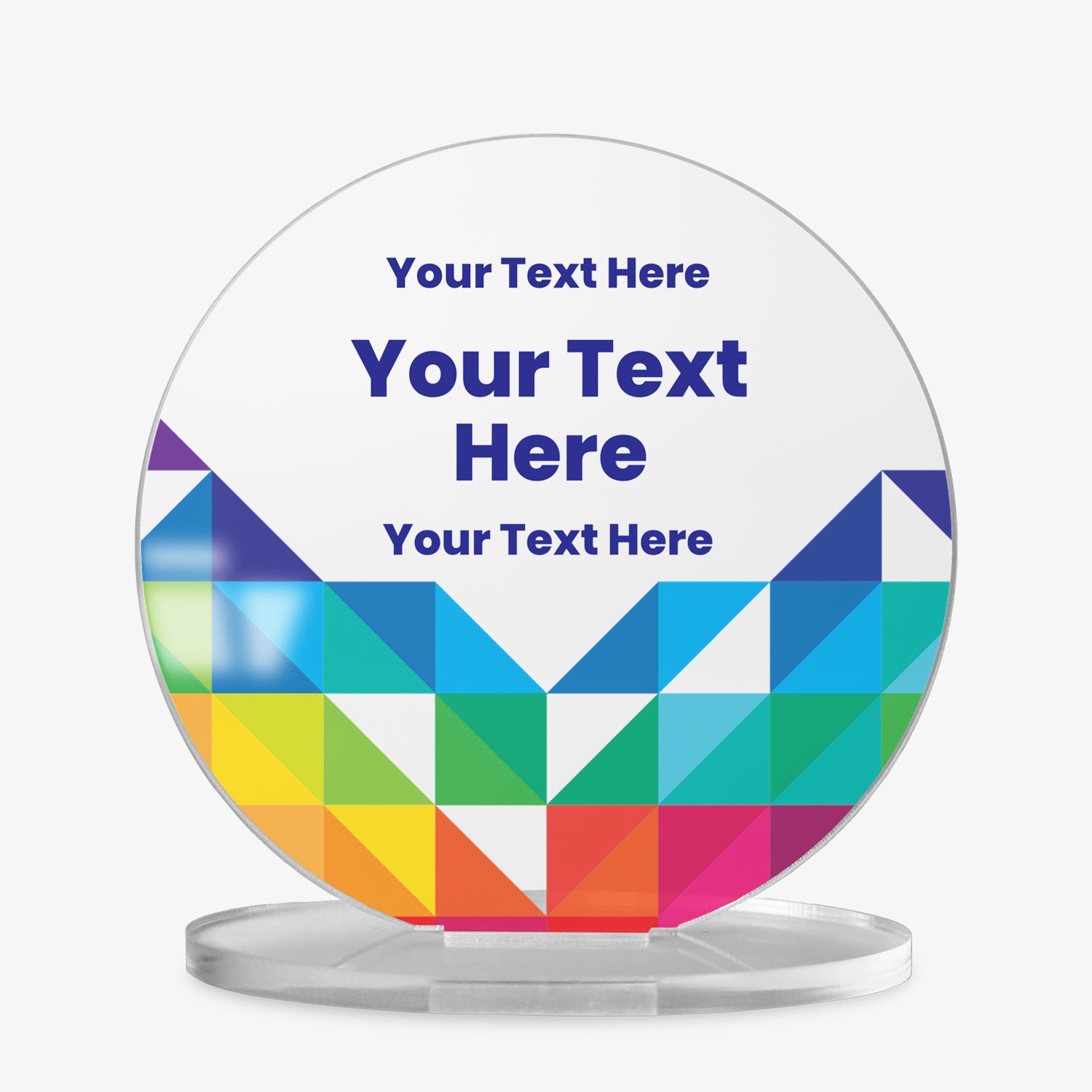 A round acrylic display plaque on a clear base. The design features three lines of customisable placeholder text reading 'Your Text Here' in bold blue font. The lower half is decorated with a vibrant geometric pattern made of colourful triangles in shades of blue, green, yellow, orange, red, and purple, arranged in a symmetrical chevron shape.