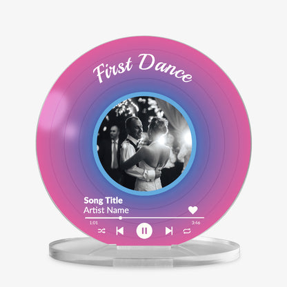 Acrylic custom vinyl record-style display with a pink and purple gradient background with a circular photo in the centre, personalised text 'First Dance' at the top, and a mock music player interface showing song title and artist name at the bottom.