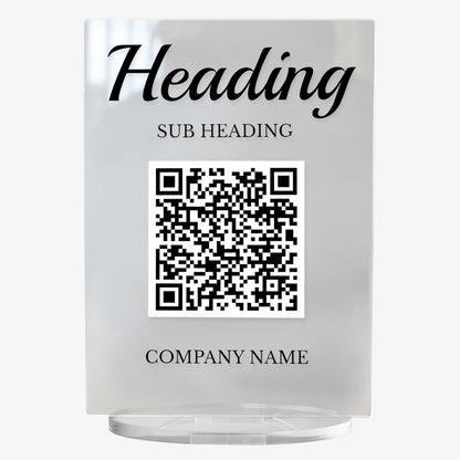 A clear acrylic sign with bold black text at the top reading 'HEADING'. Below, it another placeholder 'SUB HEADING'. A large black and white QR code is centrally displayed, and the placeholder 'COMPANY NAME' appears at the bottom. The sign stands upright on a circular clear base.
