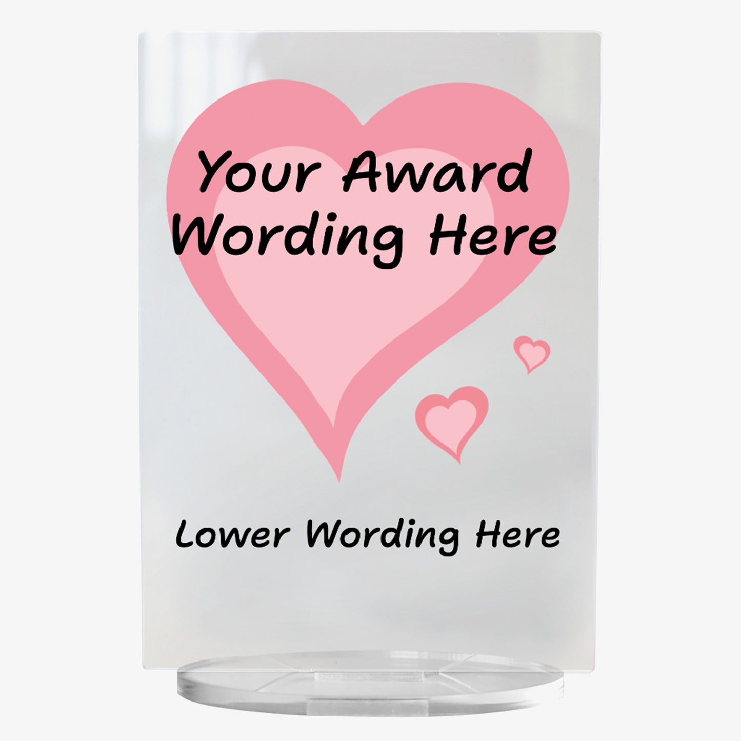 A clear acrylic award plaque standing on a circular base, featuring a large deep pink heart with pale pink centre,  with 2 smaller hearts at its tip . Overlaying the heart is placeholder text reading 'Your Award Wording Here' in bold black font. Below, additional text reads 'Lower Wording Here'. 