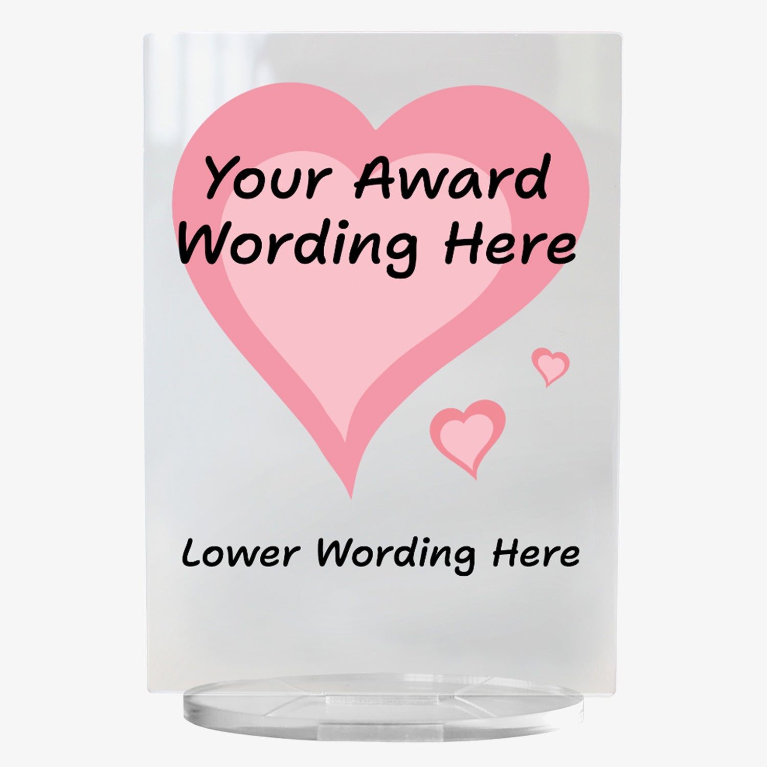 A clear acrylic award plaque standing on a circular base, featuring a large deep pink heart with pale pink centre,  with 2 smaller hearts at its tip . Overlaying the heart is placeholder text reading 'Your Award Wording Here' in bold black font. Below, additional text reads 'Lower Wording Here'. 