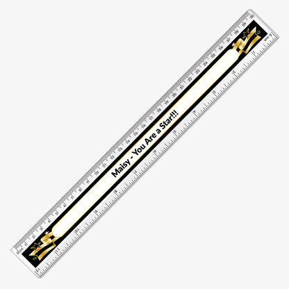 Close up of 30cm plastic ruler with a black background, decorated with a gold and black banner with space in the centre for custom wording in bold text.
