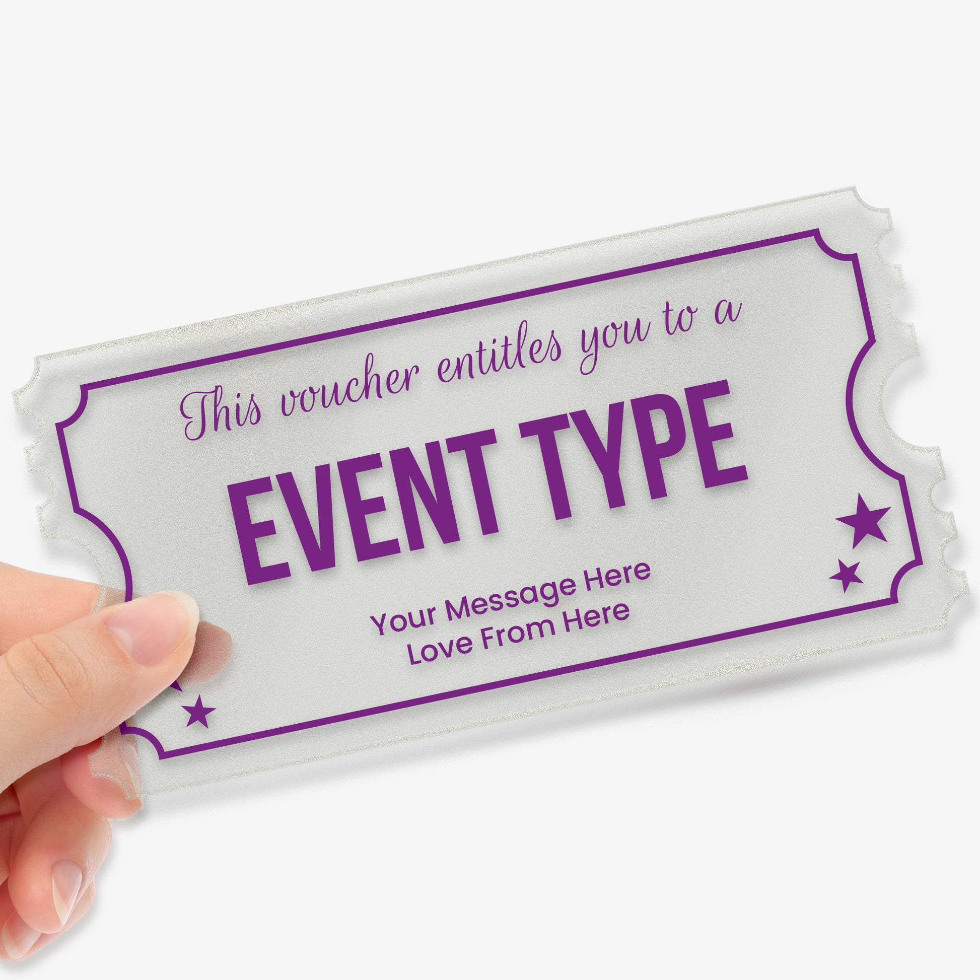 A hand holding a rectangular acrylic voucher shaped like a ticket, with decorative notched edges. The design features purple borders and stars. The placeholder text reads: 'This voucher entitles you to a EVENT TYPE. Your Message Here  Love From Here'. The overall style is elegant and celebratory, suitable as a personalised gift.