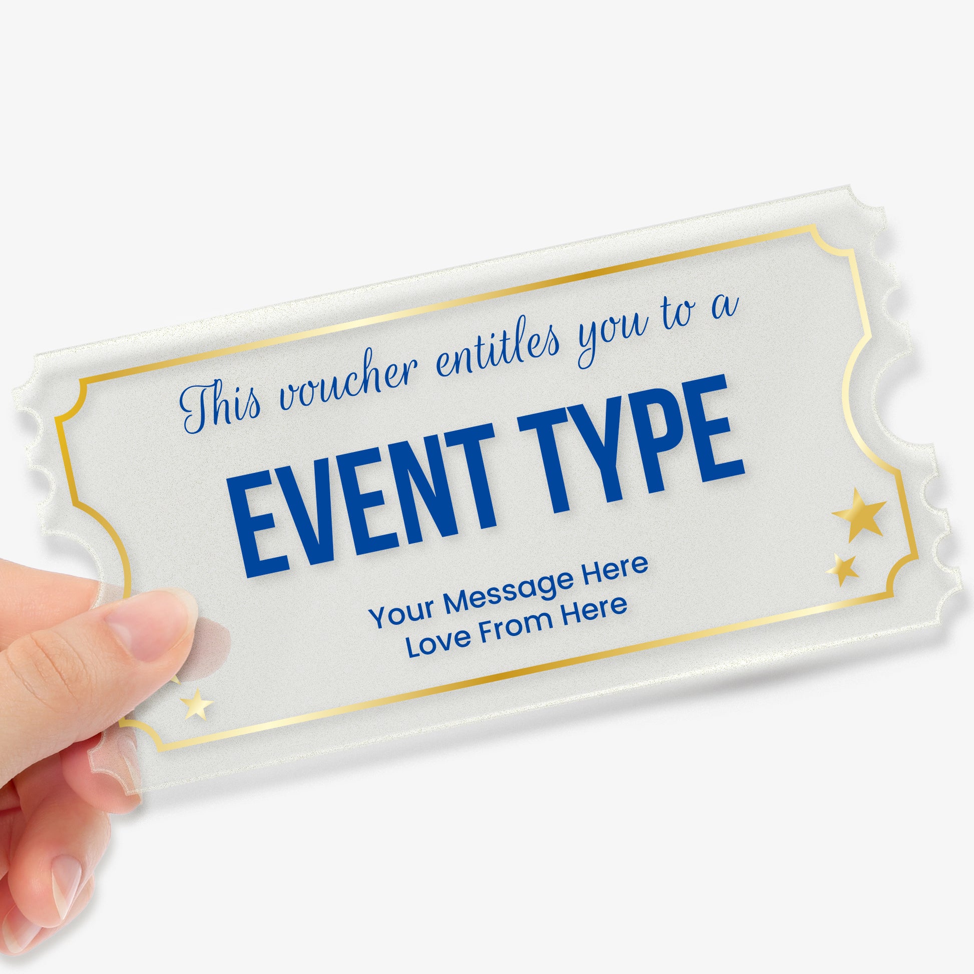 A hand holding a rectangular acrylic voucher shaped like a ticket, with decorative notched edges. The design features gold borders and stars with blue font. The placeholder text reads: 'This voucher entitles you to a EVENT TYPE. Your Message Here  Love From Here'. The overall style is elegant and celebratory, suitable as a personalised gift.