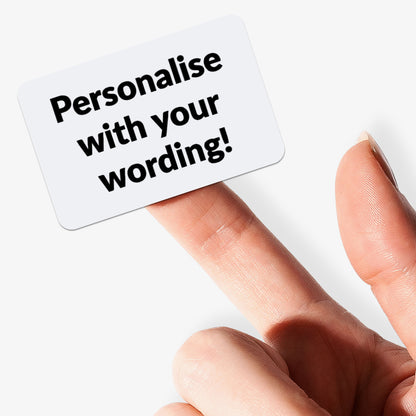 Customizable sticker with black text and white background held by a hand.