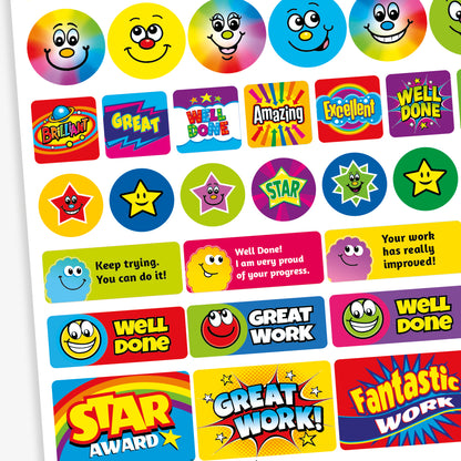 A mixed sheet of colourful reward stickers with phrases such as 'Well Done', 'Star Award', 'Amazing', and 'Excellent'. The stickers feature bold text in vibrant colours and various styles, including round and rectangular shapes. Some designs include smiley faces, stars, and rainbow effects, all intended to celebrate effort and achievement in a fun, eye-catching way.
