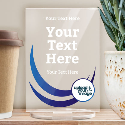 A rectangular, clear acrylic award plaque standing on a circular base. The design features curved dark blue wave graphics on the left side, and a camera icon in a circle at the bottom right, indicating space for a custom photo. The text areas are labelled 'Top Wording Here', 'YOUR AWARD TEXT HERE', and 'Lower Wording Here', allowing for personalisation. The overall style is sleek and modern, ideal for formal recognition.