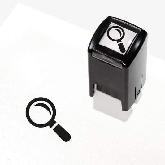 A 10mm self-inking stamp with a black outline of a magnifying glass angled to the left central to the design