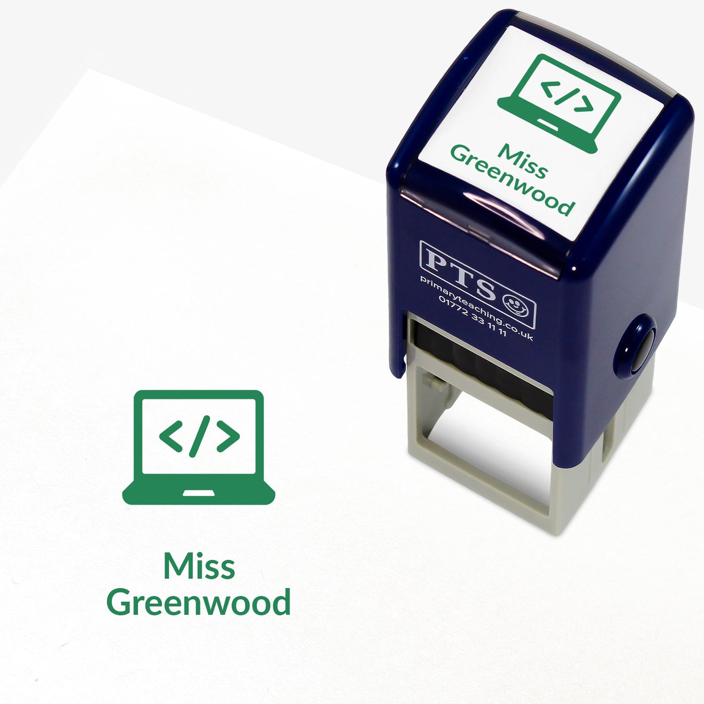 A stamper shown next to a sample stamped image on a white background. The stamp has a green outline of a laptop inside a shield shape, with placeholder text 'Miss Greenwood' on the top panel and below the stamp print.