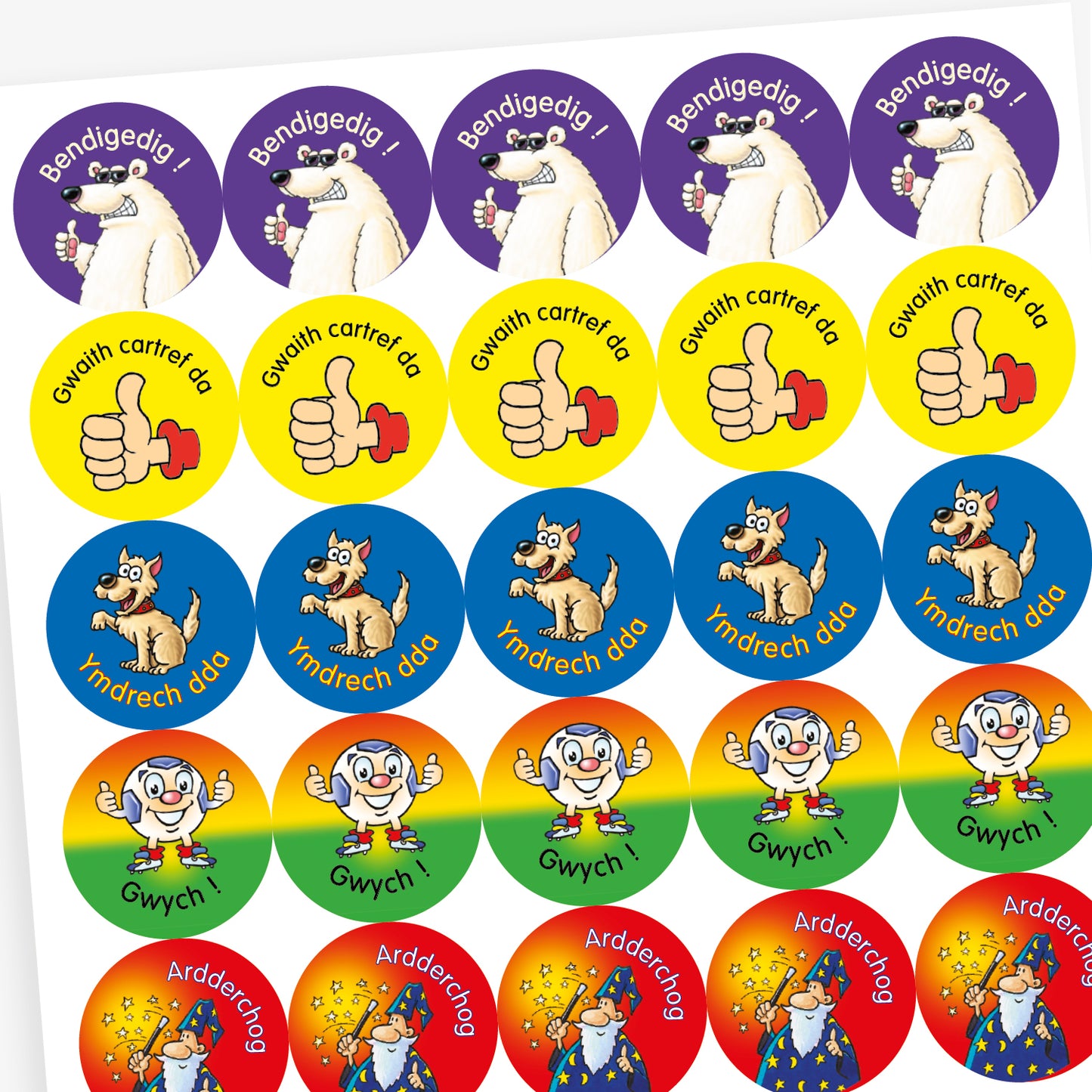 Sheet of circular stickers featuring cartoon characters and Welsh praise phrases. Includes: wizard with stars on a red background and the word 'Ardderchog'; A smiling tiger on a green background with the phrase 'Da iawn';  A thumbs-up hand on a yellow background with the phrase 'Gwaith cartref da'; A polar bear giving a thumbs up on a purple background with the word 'Bendigedig!'