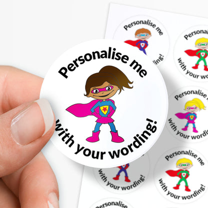 Circular sticker with superhero design and text 'Personalise me with your wording!' held in between fingers.