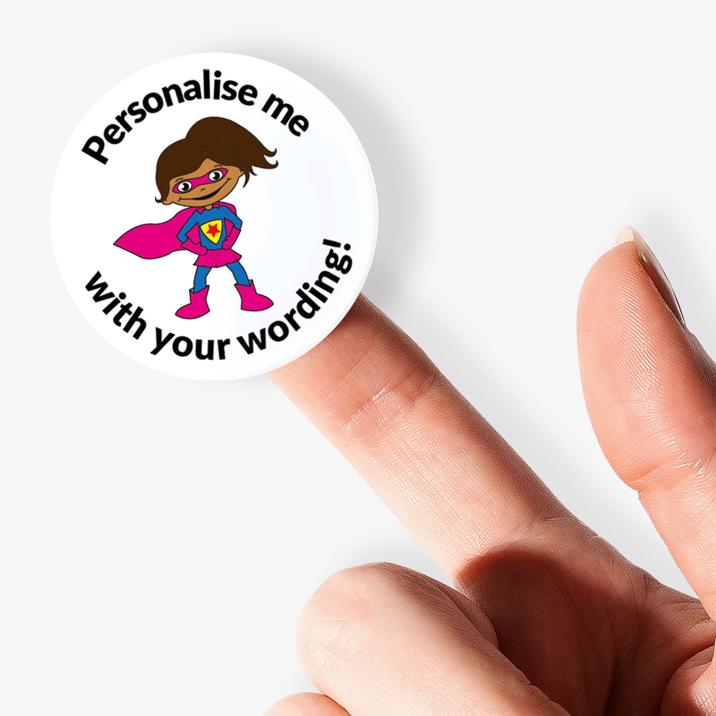 Circular sticker with superhero design and text 'Personalise me with your wording!' held between fingers.