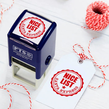 PTS Santa Express stamp on a white card with red 'Nice List' stamp, surrounded by red string on a light wooden surface.
