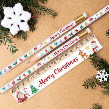 Christmas-themed pencils and ruler on a brown background with festive decorations.