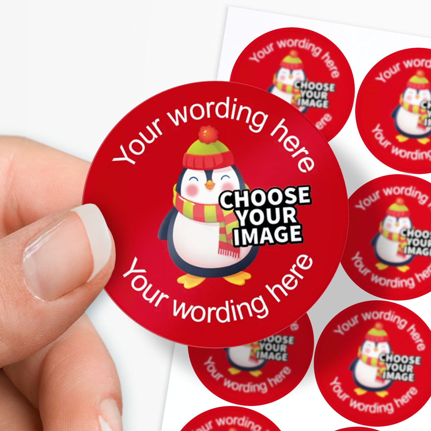 Red stickers with a penguin design and customisable text, held by a hand.
