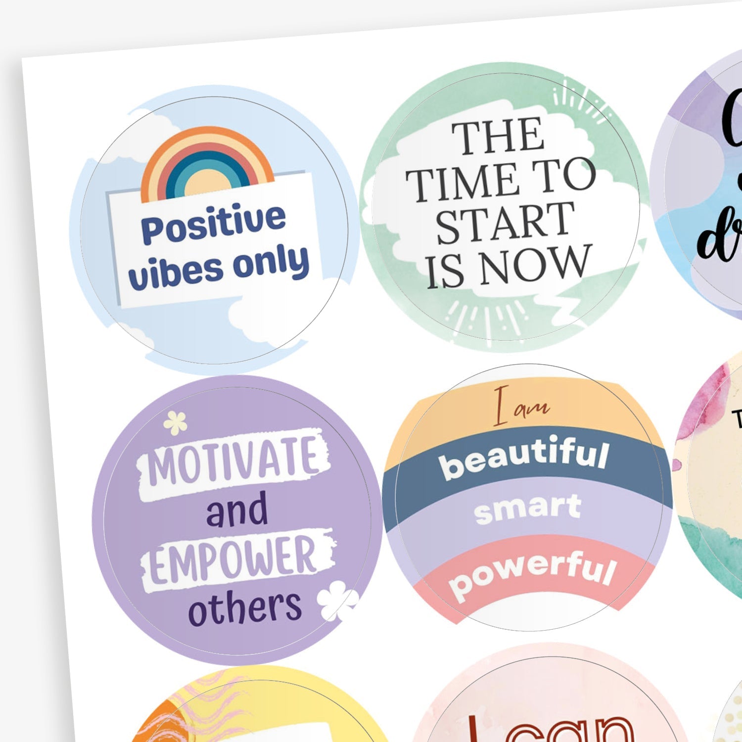 A collection of circular motivational stickers with pastel backgrounds and uplifting phrases. Visible stickers include: 'Positive vibes only' with a rainbow; 'THE TIME TO START IS NOW' on a green abstract background; 'Motivate and EMPOWER others' on a purple background with stars; 'I am beautiful, smart, powerful' written on layered coloured banners.