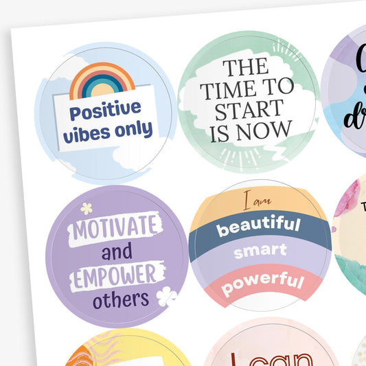A collection of circular motivational stickers with pastel backgrounds and uplifting phrases. Visible stickers include: 'Positive vibes only' with a rainbow; 'THE TIME TO START IS NOW' on a green abstract background; 'Motivate and EMPOWER others' on a purple background with stars; 'I am beautiful, smart, powerful' written on layered coloured banners.