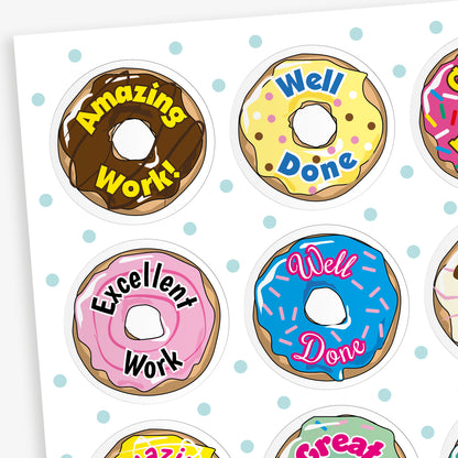 100 32mm vanilla-scented doughnut stickers in assorted pastel colours, each featuring phrases like 'Well Done', 'Great Work', and 'Brilliant Effort' in bold fonts; designed for rewarding achievements.