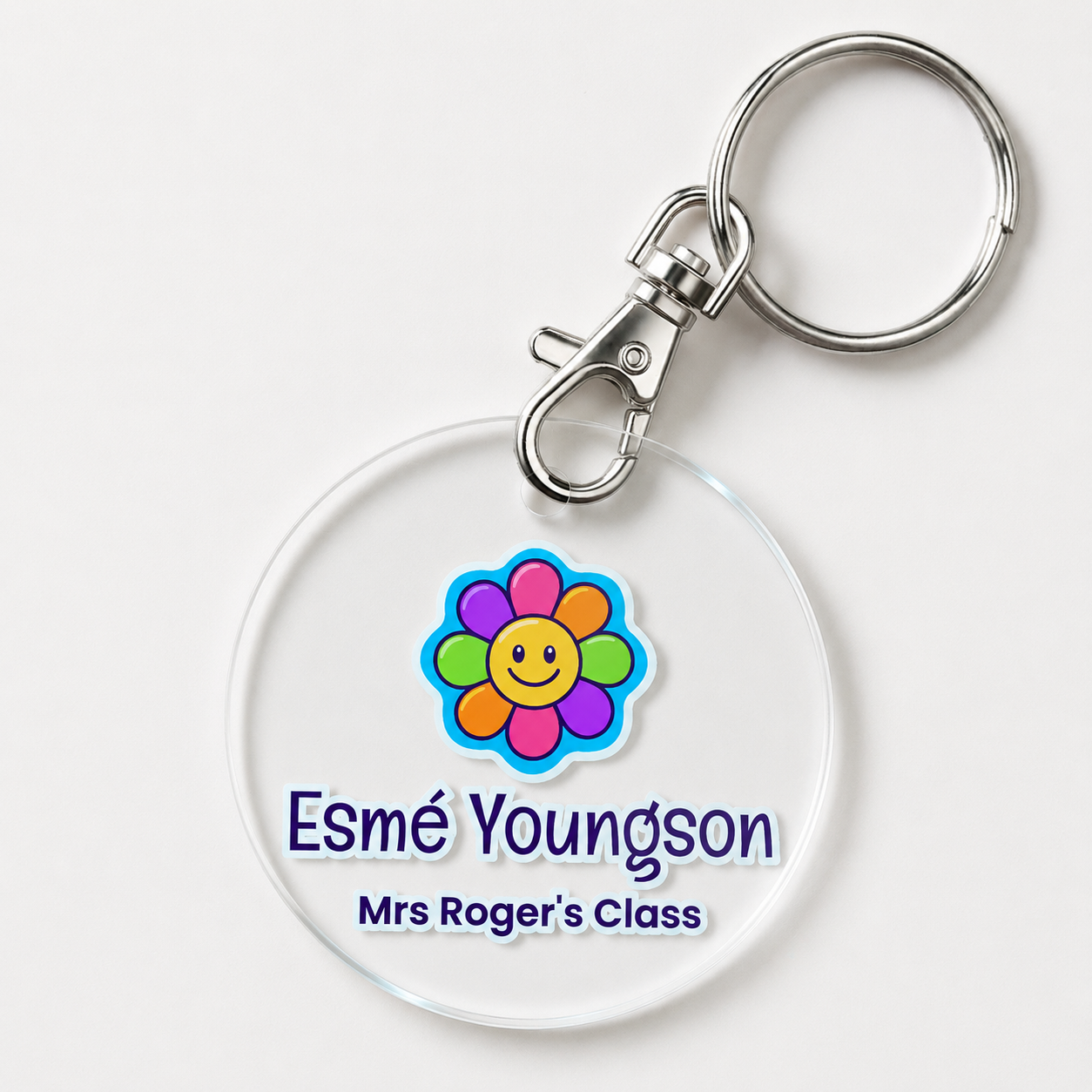 A personalized acrylic bag tag featuring a flower and example text 'Esme Youngson Mrs Roger's Class'. 