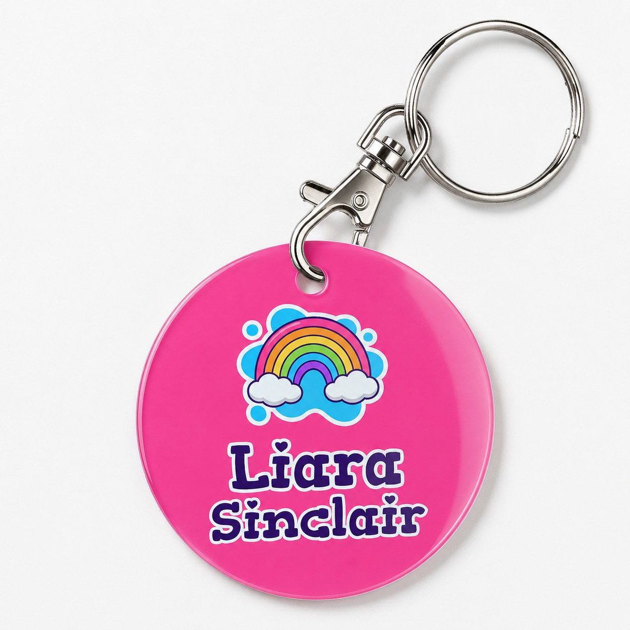 A personalized acrylic bag tag featuring a rainbow and example text 'Liara Sinclair'. 