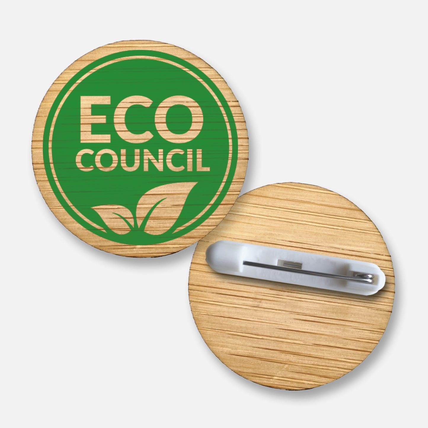 A 38mm circular badge crafted from natural bamboo, featuring the phrase 'ECO COUNCIL'  inverted through green overlay, encircled by a green double line and natural leaf.  Pin fastening on the reverse side.