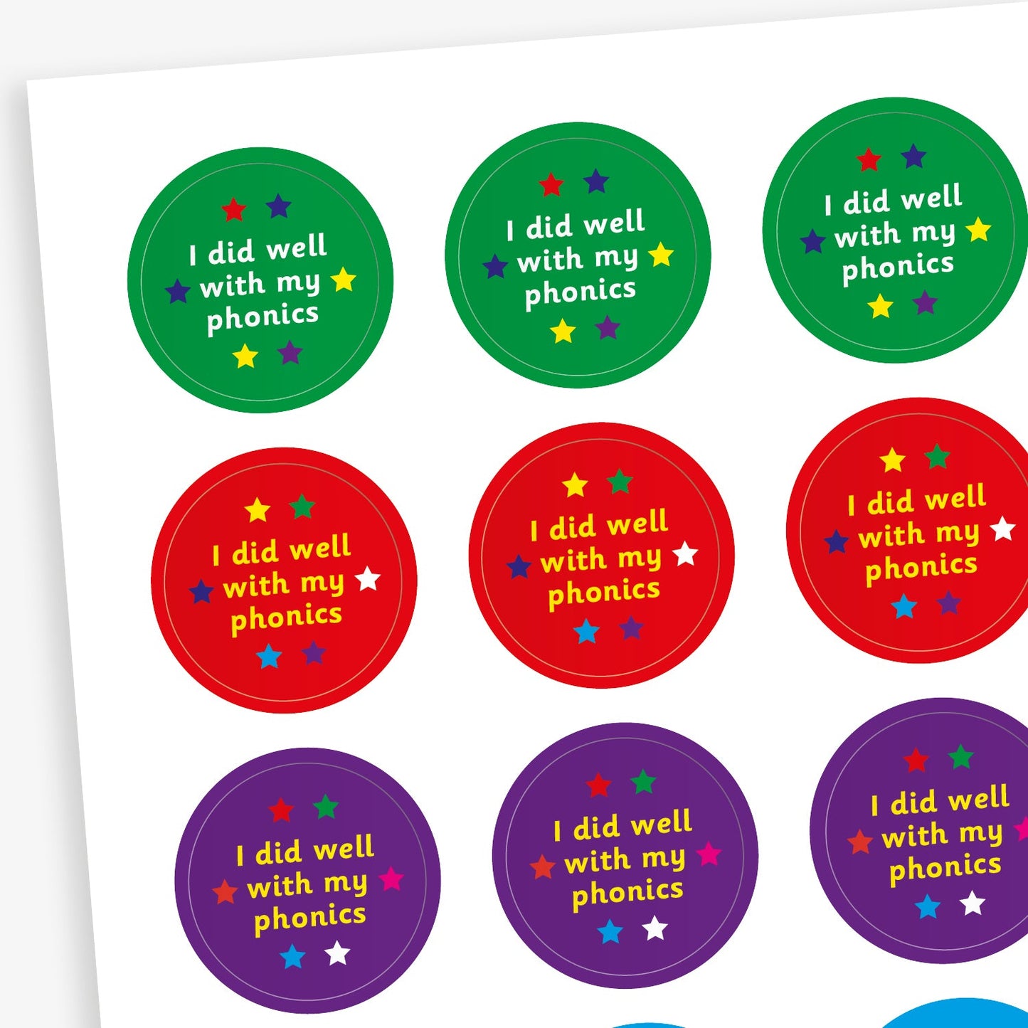 A sheet of colourful circular stickers featuring 'I did well with my phonics' on backgrounds including green, red, purple and cyan.