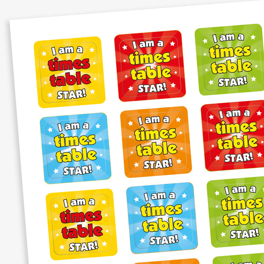 A sheet of square stickers each with the phrase 'I am a times table STAR!' in starburst backgrounds with emissions of small stars in yellow, red, orange, green and blue.