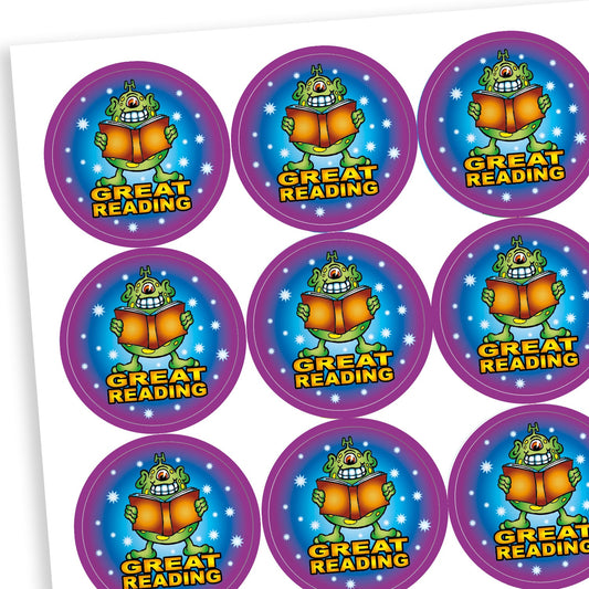 A sheet of round reward stickers featuring a cartoon monster holding an open book with a joyful expression. Each sticker has a blue centre with stars, a purple border, and the text 'GREAT READING' in bold yellow letters below the monster.