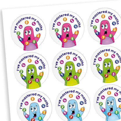 A sheet of circular reward stickers featuring colourful cartoon characters with raised hands juggling numbered circles. The text on each sticker reads 'I've mastered my maths' in bold blue letters. The characters appear in various bright colours including pink, green, and blue, celebrating achievement in mathematics.