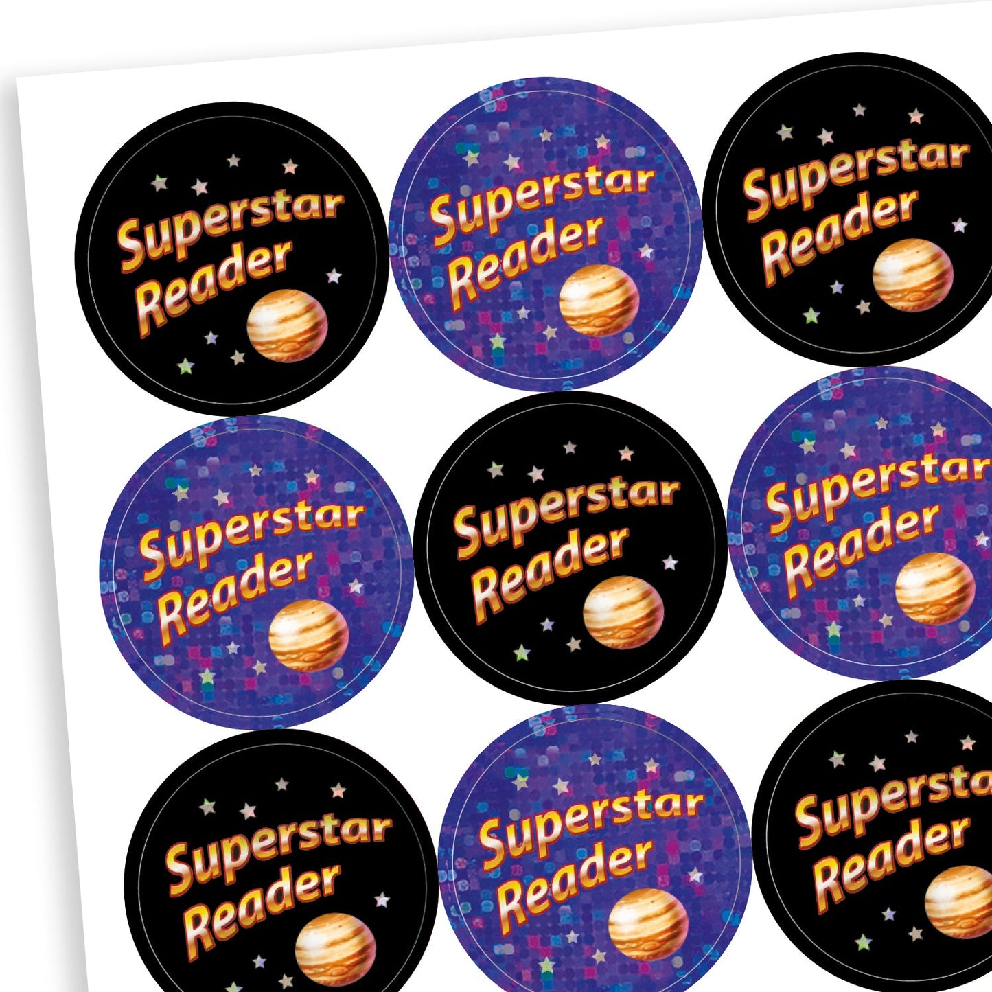 A sheet of circular, holographic reward stickers with the phrase 'Superstar Reader' in bright text. Each sticker features a planet illustration and a starry background. Half the stickers have a black background with orange and white text, while the other half have a sparkly purple background with blue and orange text, creating a cosmic theme.