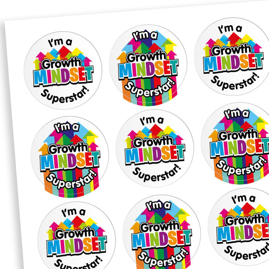 A sheet of round stickers, each with the phrase 'I'm a Growth Mindset Superstar!' in bold, playful text. The word 'Mindset' is especially colourful, with each letter in a different bright colour and arrows pointing upwards above it, symbolising growth. 