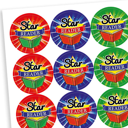 A sheet of circular reward stickers with the phrase 'Star Reader' in bold black and white text over a red and blue banner. Each sticker features a colourful open book and a tie-dye style background in various bright colours such as blue, green, red, purple, and orange.