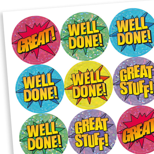 A sheet of colourful, holographic comic-style reward stickers with bold phrases in yellow text, including 'GREAT!', 'WELL DONE!', and 'GREAT STUFF!'. Each sticker has a circular shape with a starburst or dotted background in bright colours like red, green, blue, yellow, and purple, giving a fun, energetic look.