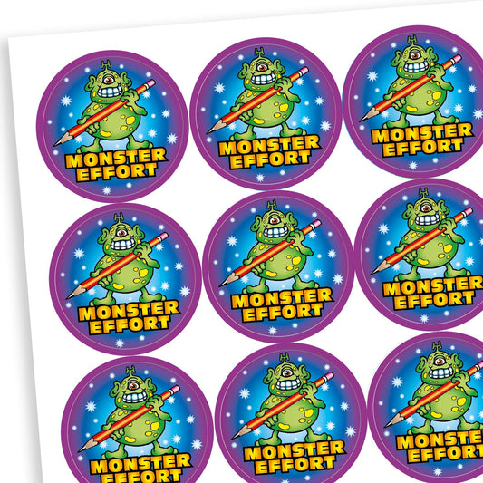 A sheet of circular reward stickers with the phrase 'MONSTER EFFORT' in bold yellow text. Each sticker features a green cartoon monster with purple spots, holding a giant pencil. The background is dark blue with stars, and the border is bright purple.