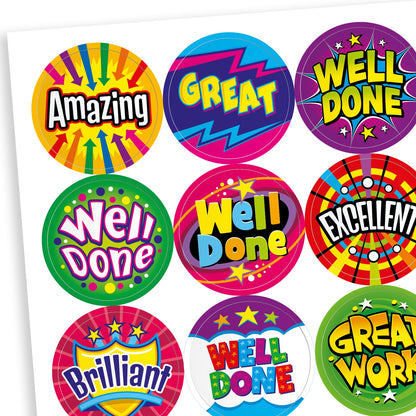 Sheet of colourful reward stickers featuring a variety of fun designs including solar, arrows, shields, and stars. Messages include 'Well Done', 'Amazing', 'Great', 'Excellent', and 'Great Work'.