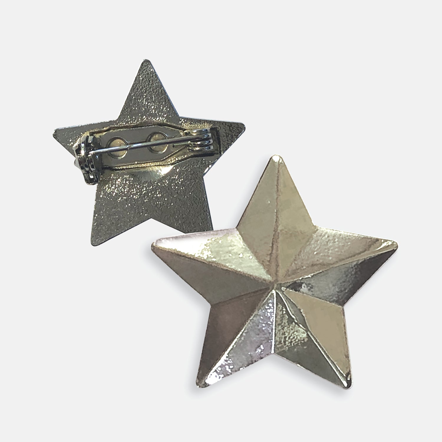 Silver-coloured pin badge in the shape of a 3D star, with one badge showing the front and another showing the back with a pin fastening.