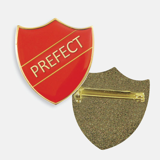 Red enamel prefect badge in the shape of a shield with gold trim and diagonal gold line either side of the word 'PREFECT' in capital letters. The reverse side shows a textured gold back with a pin fastening.