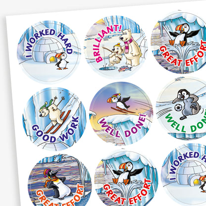 A sheet of circular reward stickers with phrases including 'I worked hard', 'Good Work', 'Well done' and 'Great Effort' in colourful text. Each sticker features arctic-themed cartoon animals such as puffins, polar bears, and walruses, engaging in playful activities against icy, snowy backdrops. 